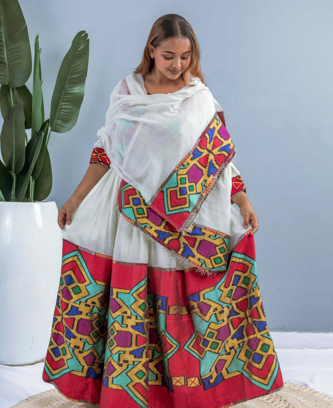 A woman wearing a modern Habesha dress with traditional dress colours embedded