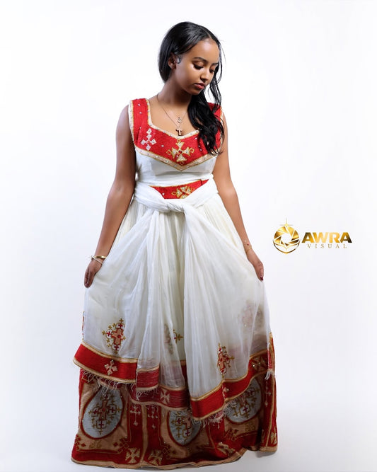 Woman wearing a white and red traditional Red Habesha Libs with gold accents on a white background, featuring the AWRA brand.