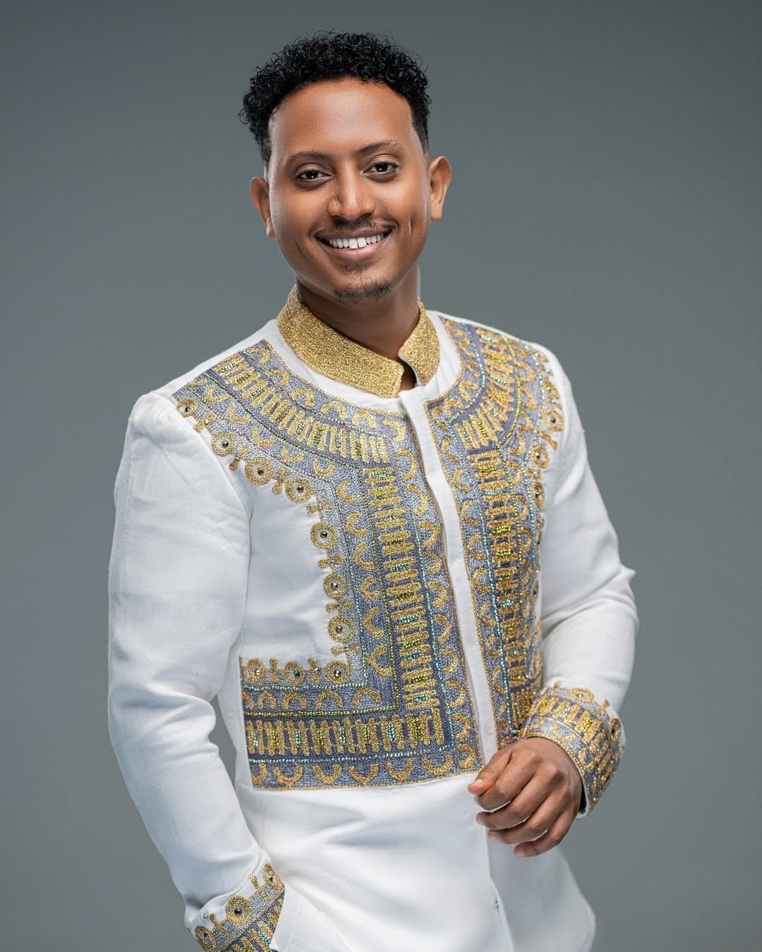 Man wearing a Habesha Men’s Shirt with gold details on a gray background