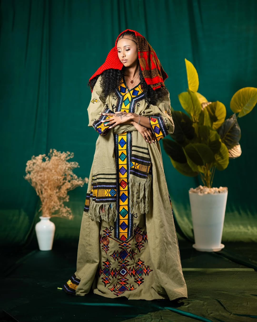 Woman in Gonder Fetel Ethiopian Dress with colorful patterns against a green background