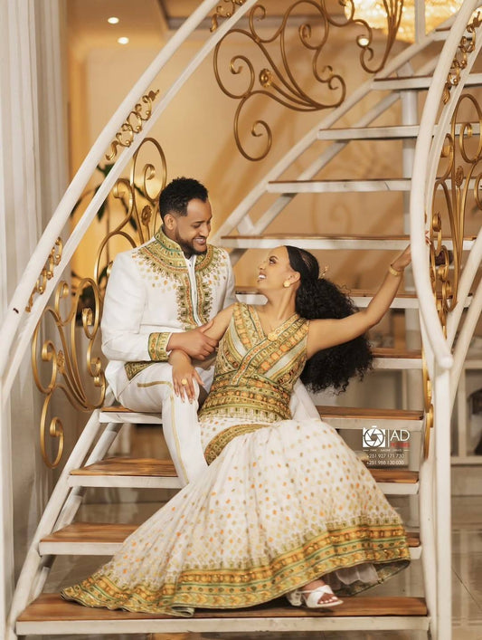 Couple in forma Habesha Men’s Wedding Outfit attire sitting on a decorative staircase