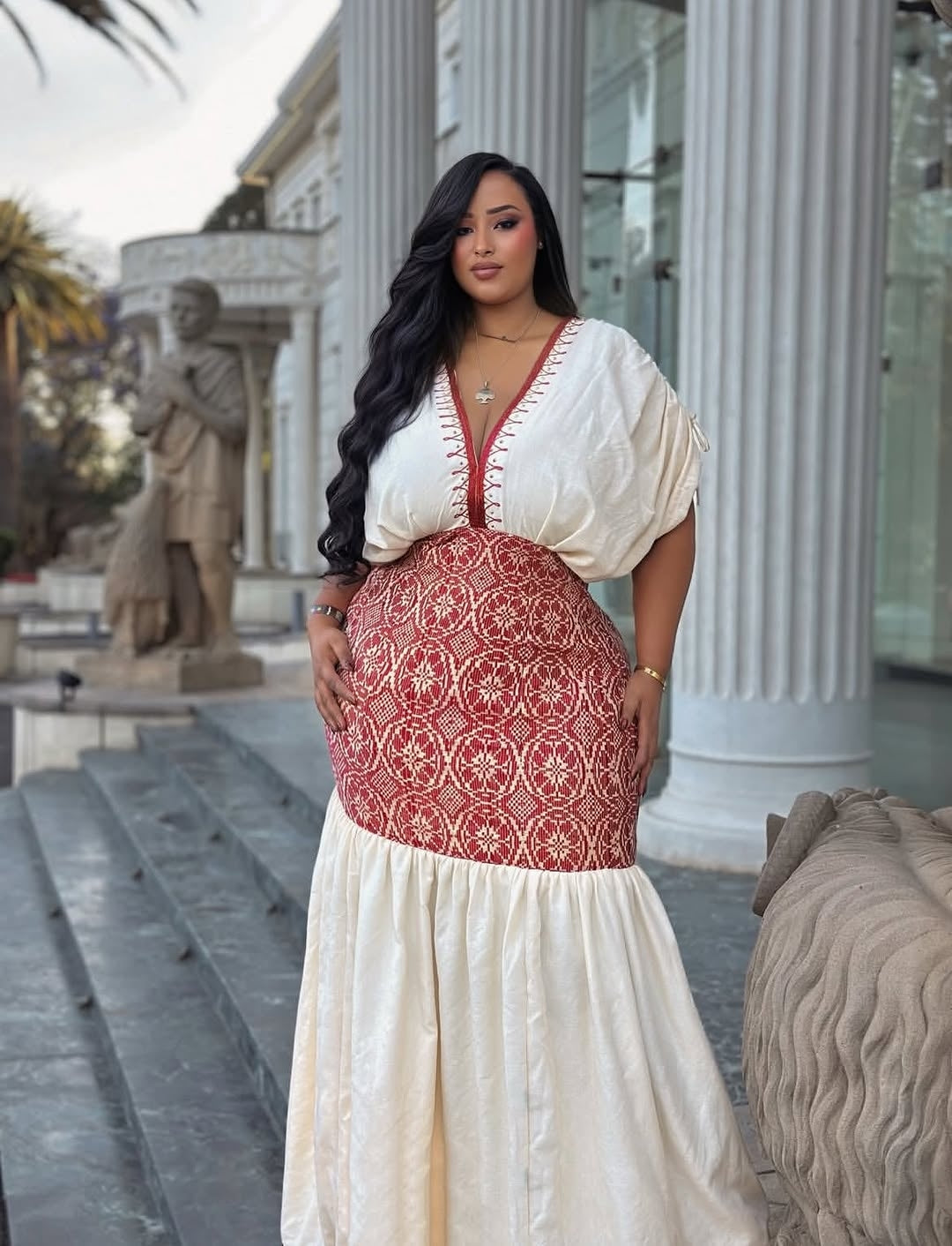 Woman in a white and red Ethiopia traditional dress standing in front of classical architecture
