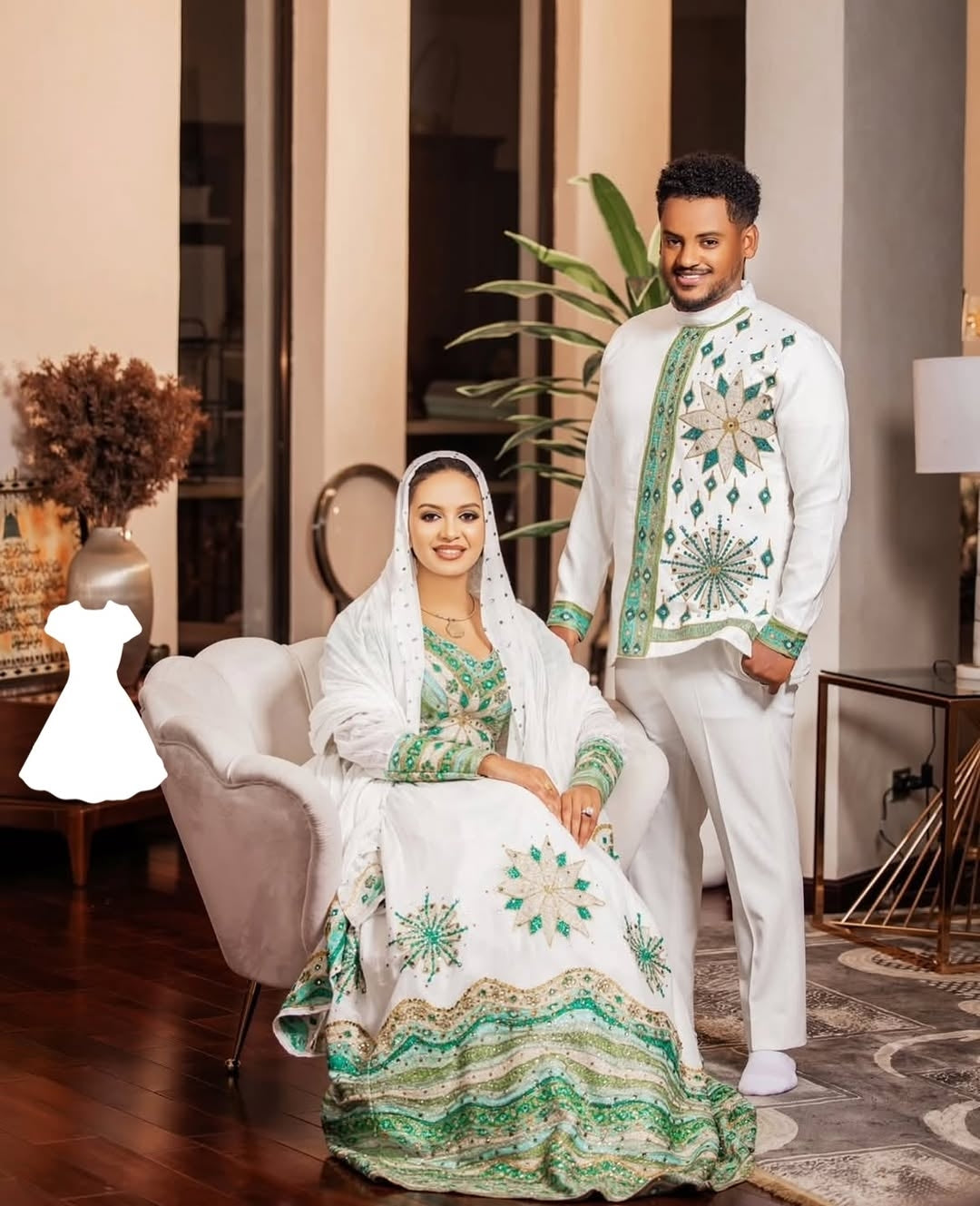 Man and woman in traditional Ethiopian traditional dress sitting in a room with decor elements.