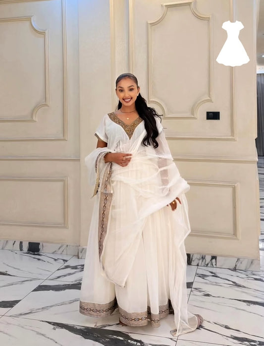 Woman in a white traditional habesha kemis standing in a stylish interior setting