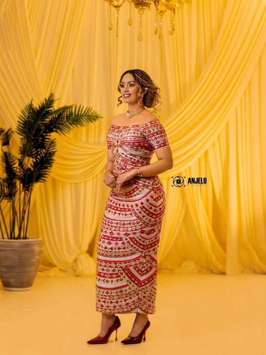 Woman in a patterned Habesha Kemis standing against a yellow curtain backdrop with a plant to her left.