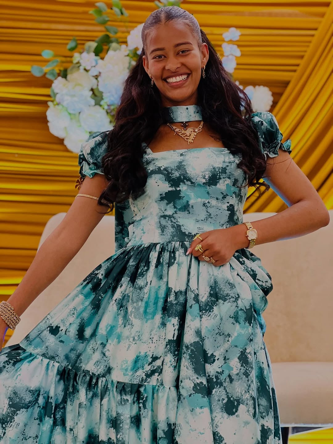 Woman in a floral Green Habesha Chiffon standing in front of a yellow wall with floral decorations