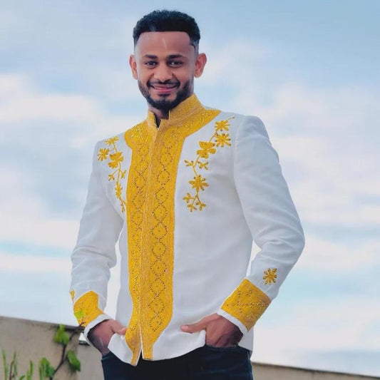 Man wearing a white and yellow Habesha Men’s Shirt against a cloudy sky.