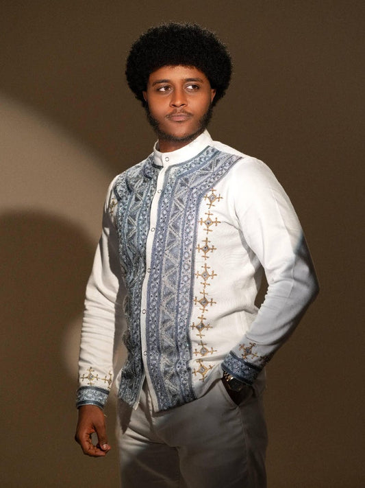 Man wearing a patterned vest over a white Ethiopian Men’s Shirt against a brown background