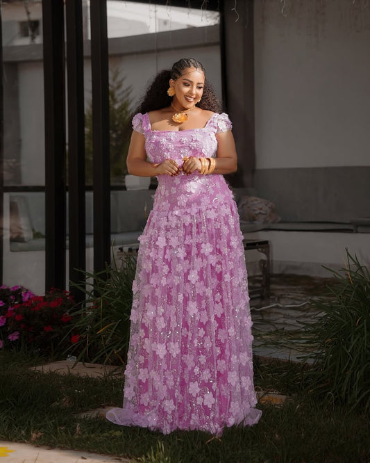 Woman in a pink floral Habesha Shiffon standing outdoors.