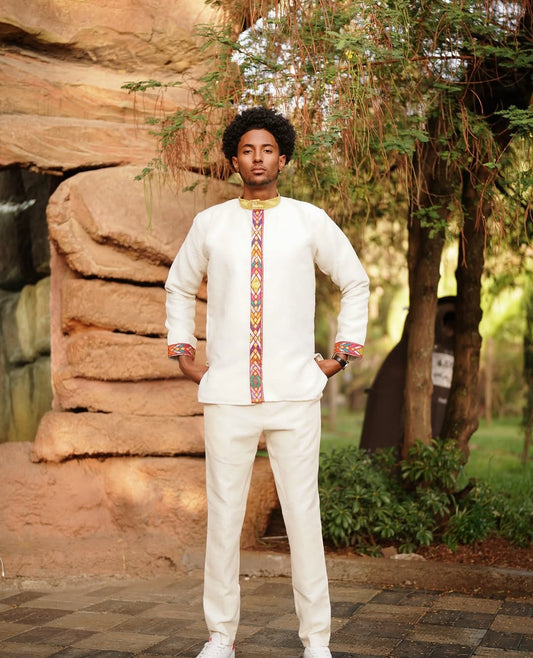 Person wearing a Habesha Men’s Outfit with colorful patterns in an outdoor setting.
