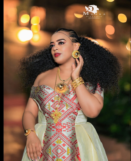 Woman in traditional attireHabesha Wedding Dress with jewelry against a blurred background
