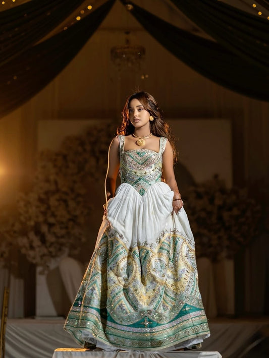 Woman in a Green Habesha Wedding Kemis with intricate patterns in a decorated indoor setting