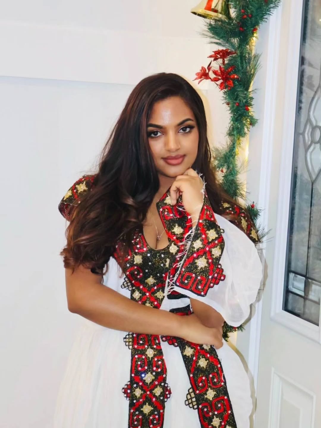 Woman wearing a festive Ethiopian traditional dress with Christmas decorations in the background