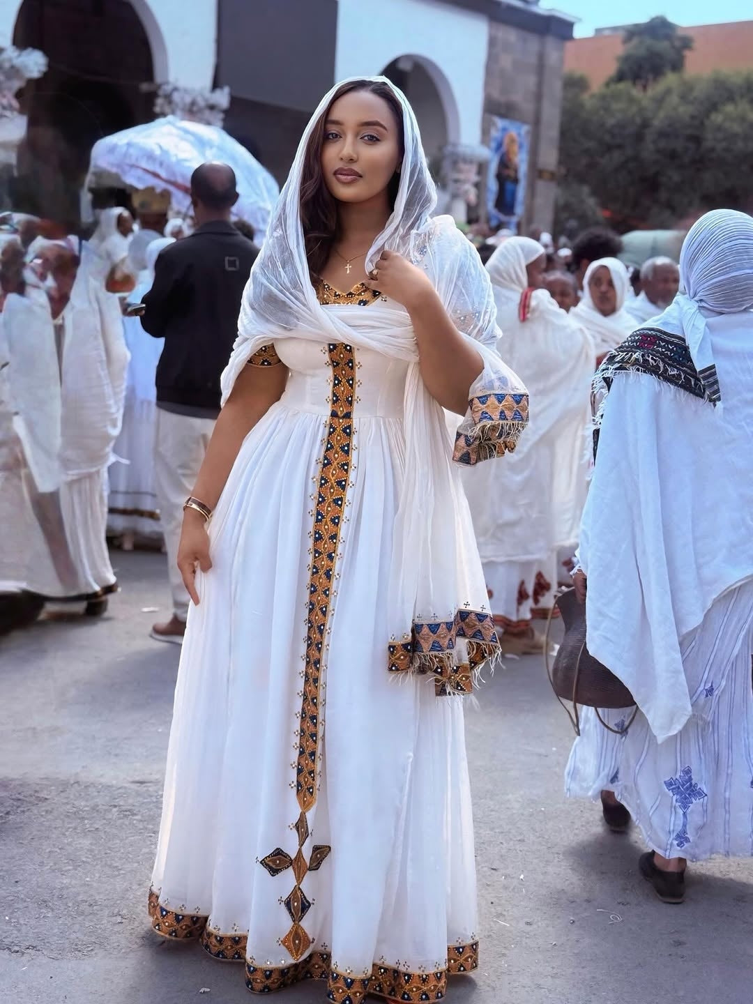 Woman in a Ethiopian Habesha Dress with decorative patterns walking in a crowd.