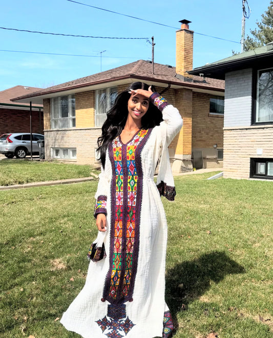 A smiling Habesha woman wearing a custom Habesha dress in accurately measured size 
