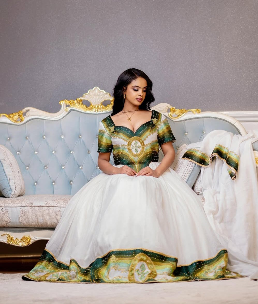 A woman wearing a modern habesha dress for diaspora event, sitting in a couch