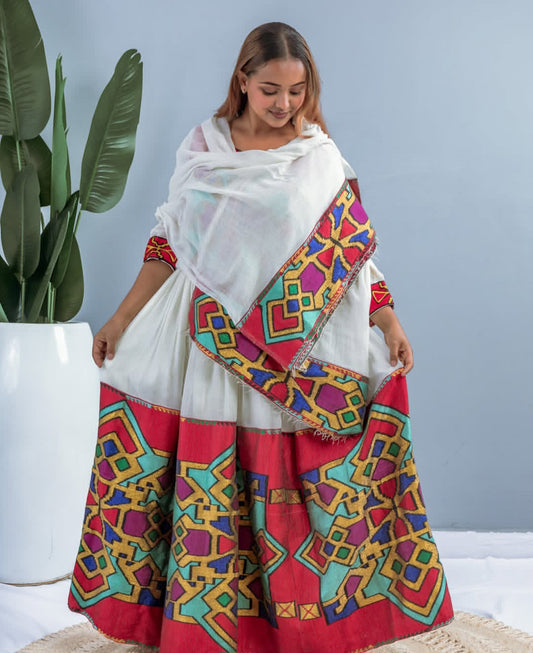 A woman wearing a modern Habesha dress with traditional dress colours embedded