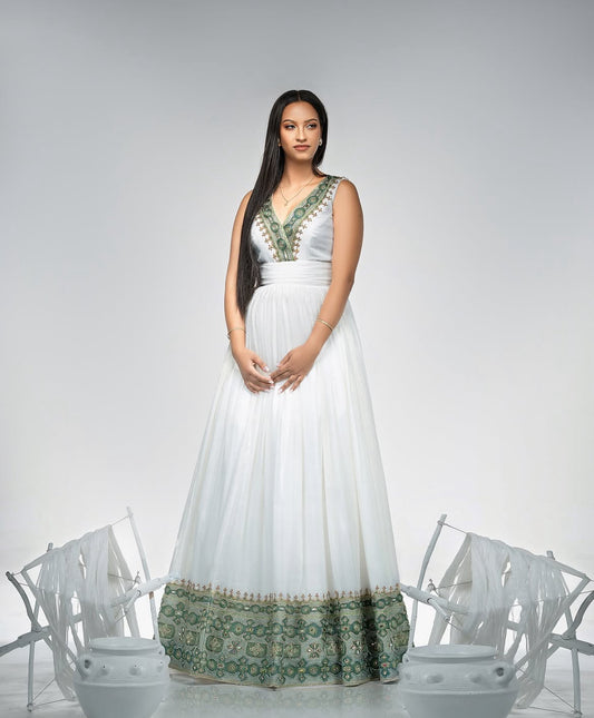 Woman wearing a white dress with green patterns against a gray background