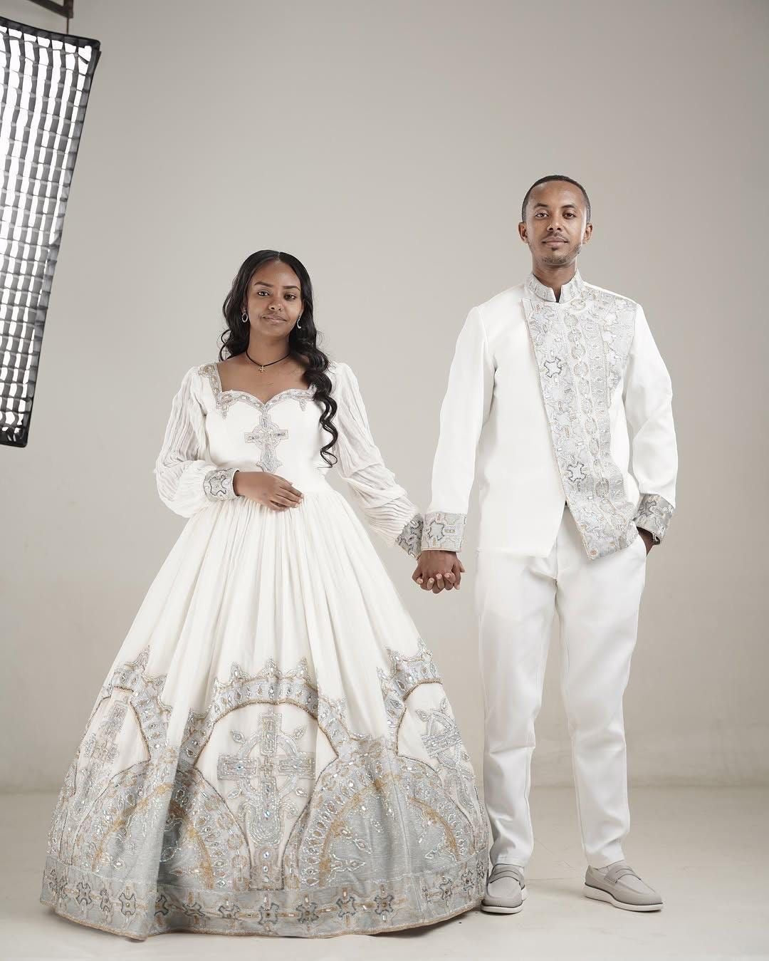 Man and woman in formal White Habesha Couple Setholding hands against a neutral background