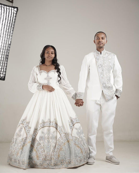 Man and woman in formal White Habesha Couple Setholding hands against a neutral background