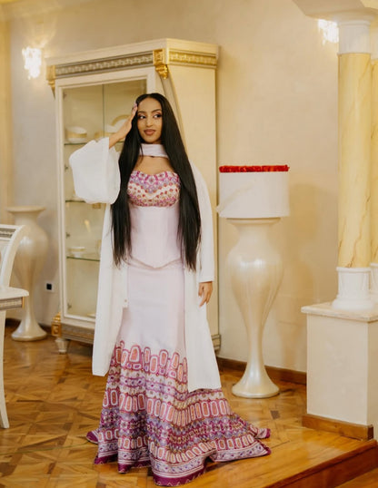 Woman in a patterned Habesha Dress standing in an elegant interior setting