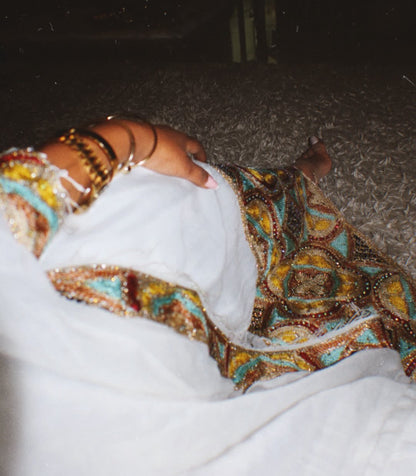 Person wearing a colorful Habesha Zuria beaded garment in a snowy outdoor setting
