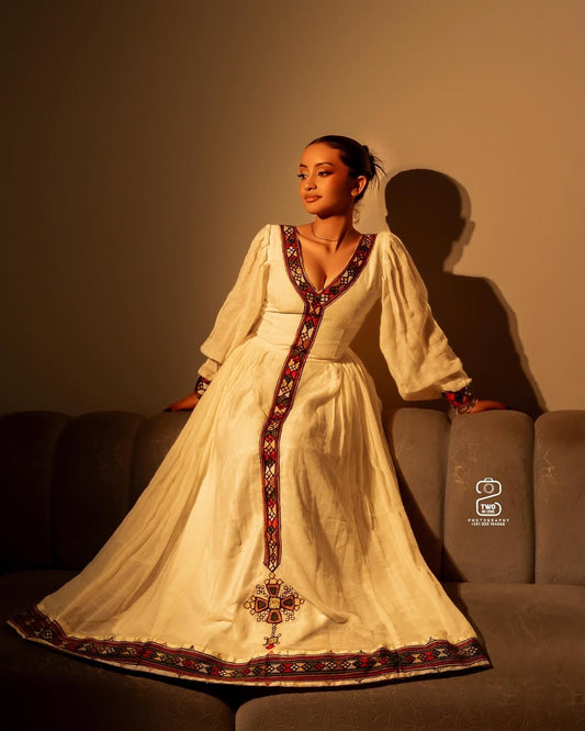 Woman in a traditional Ethiopian Dress  sitting on a couch with a warm glow