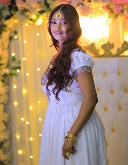 Woman in a white Habesha Dress with floral decorations and string lights in the background