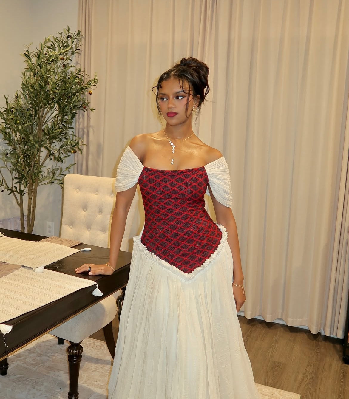 Woman wearing a red and white Ethiopian Dress with a patterned top in an indoor setting.