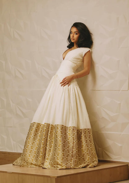 Woman wearing a white and gold dress against a plain background