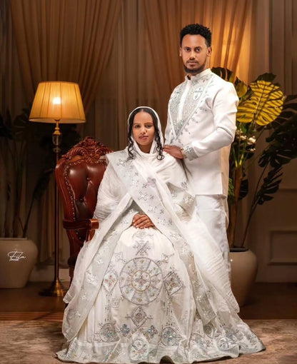 Man and woman in formal white attire posing together in a decorated room.