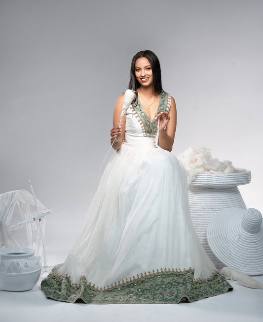Woman in a white and green traditional habesha dress  with decorative elements on a gray background