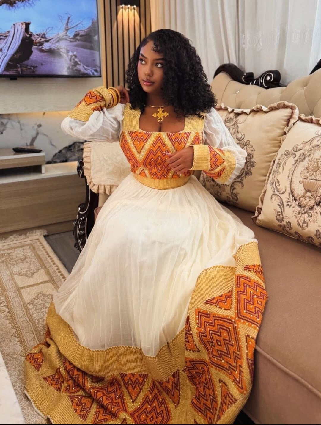 Woman in a traditional outfit sitting on a couch in a living room.