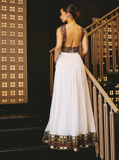 Woman in a white habesha dress with intricate patterns walking up a staircase.