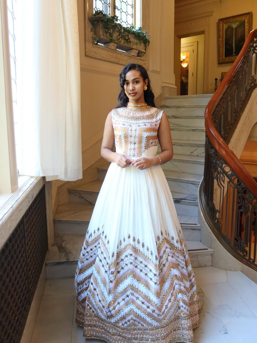 Woman in a patterned wedding habesha dress standing in a grand staircase