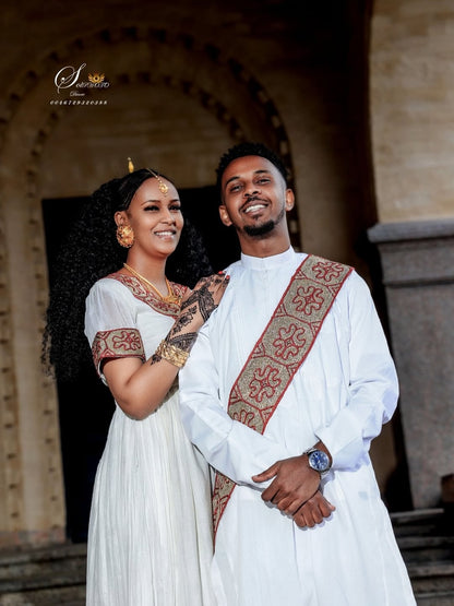 Couple in traditional Red Matching Habesha Set  standing together in front of an architectural background