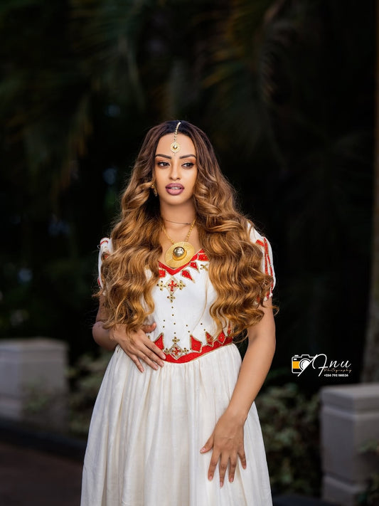 Woman in a white and red dress with long hair, standing outdoors.