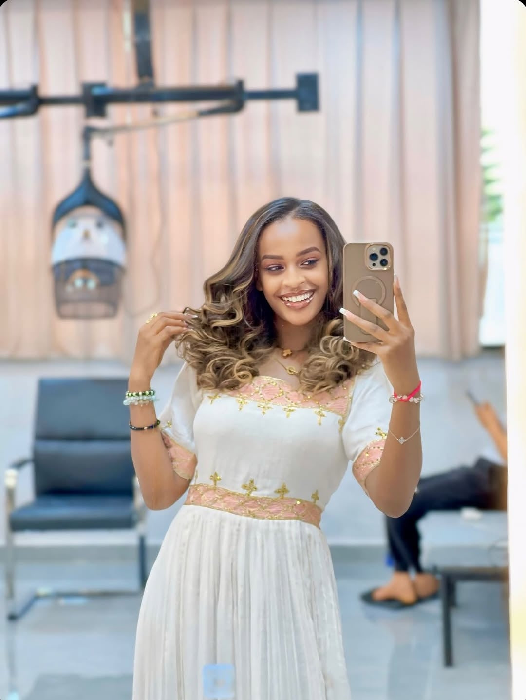 Woman taking a selfie in a white dress with floral details in an indoor setting.