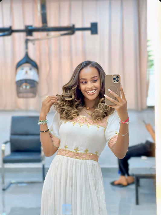 Woman taking a selfie in a white dress with floral details in an indoor setting.