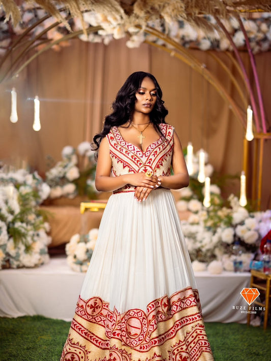 Woman in a red and white Ethiopian Traditional Dress embroidered red Ethiopian traditional dress standing in a decorated outdoor setting with flowers and candles.