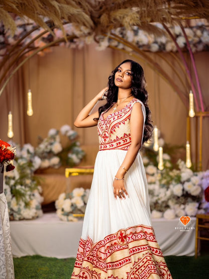 Woman in a white and red red Ethiopian traditional dress standing in a decorated indoor setting with flowers and lights.