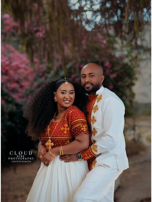Couple in traditional Red and White Habesha Matching Couple Set standing together with a blurred natural background