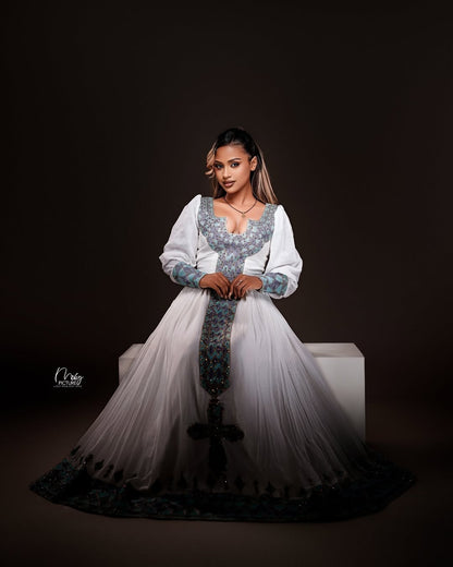 Woman in a white and blue embroidered traditional outfit on a dark background
