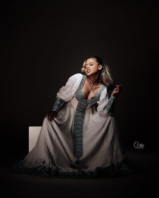 Woman in a historical costume Habesha Zuria on a white pedestal against a dark background
