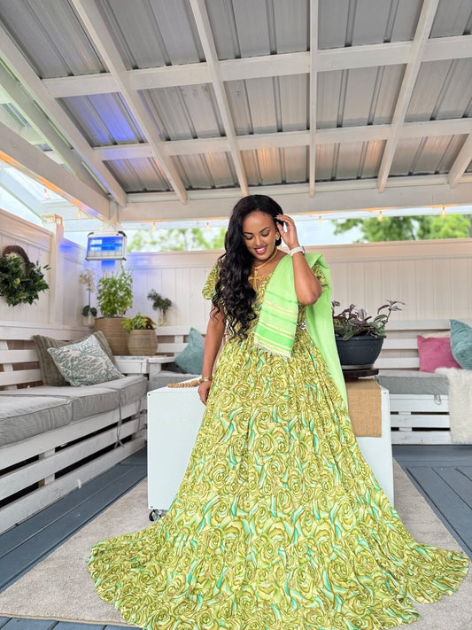 A woman wearing a vibrant lime green and yellow patterned traditional Habesha chiffon  with a matching dupatta, standing in a modern outdoor patio lounge setting.