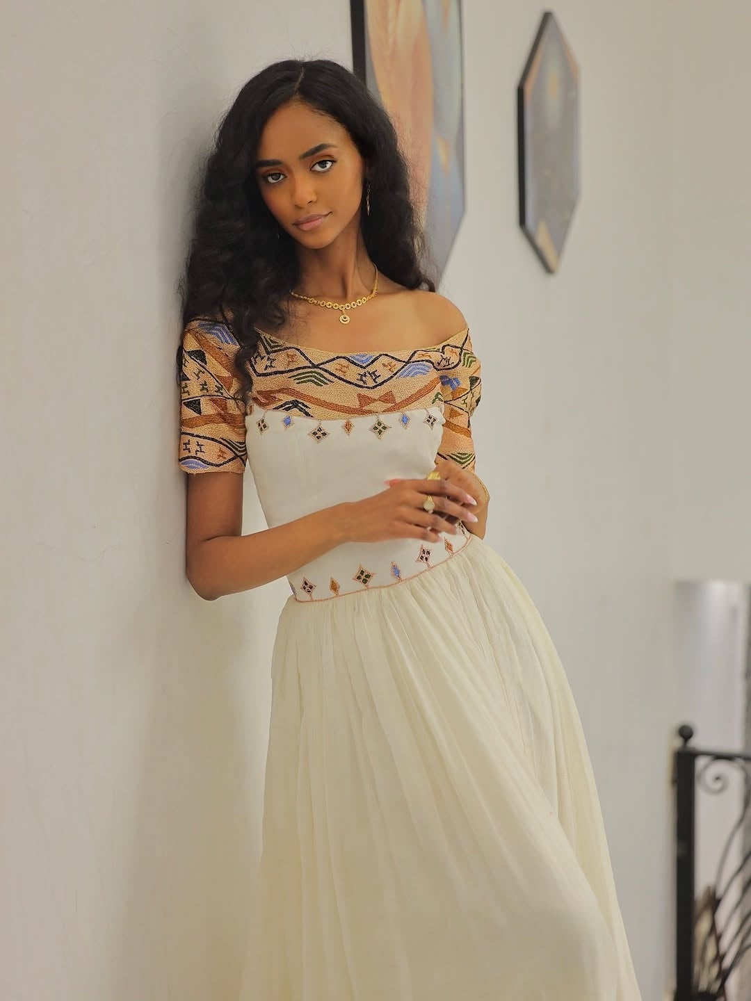 Woman wearing a patterned top and beige Gold Habesha Libs indoors.