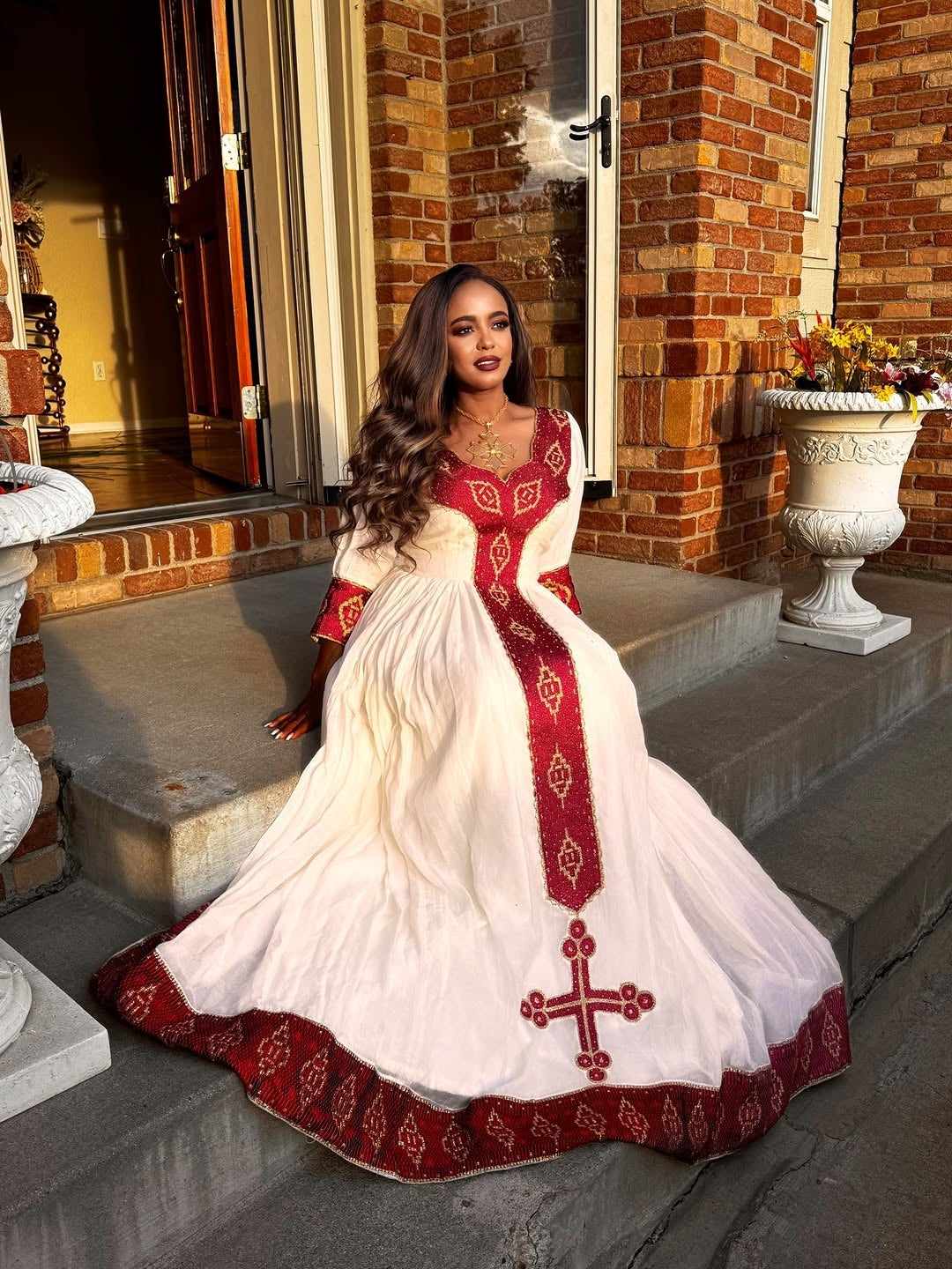 Woman in a white and red traditional Ethiopian Libs standing on steps outside a building.
