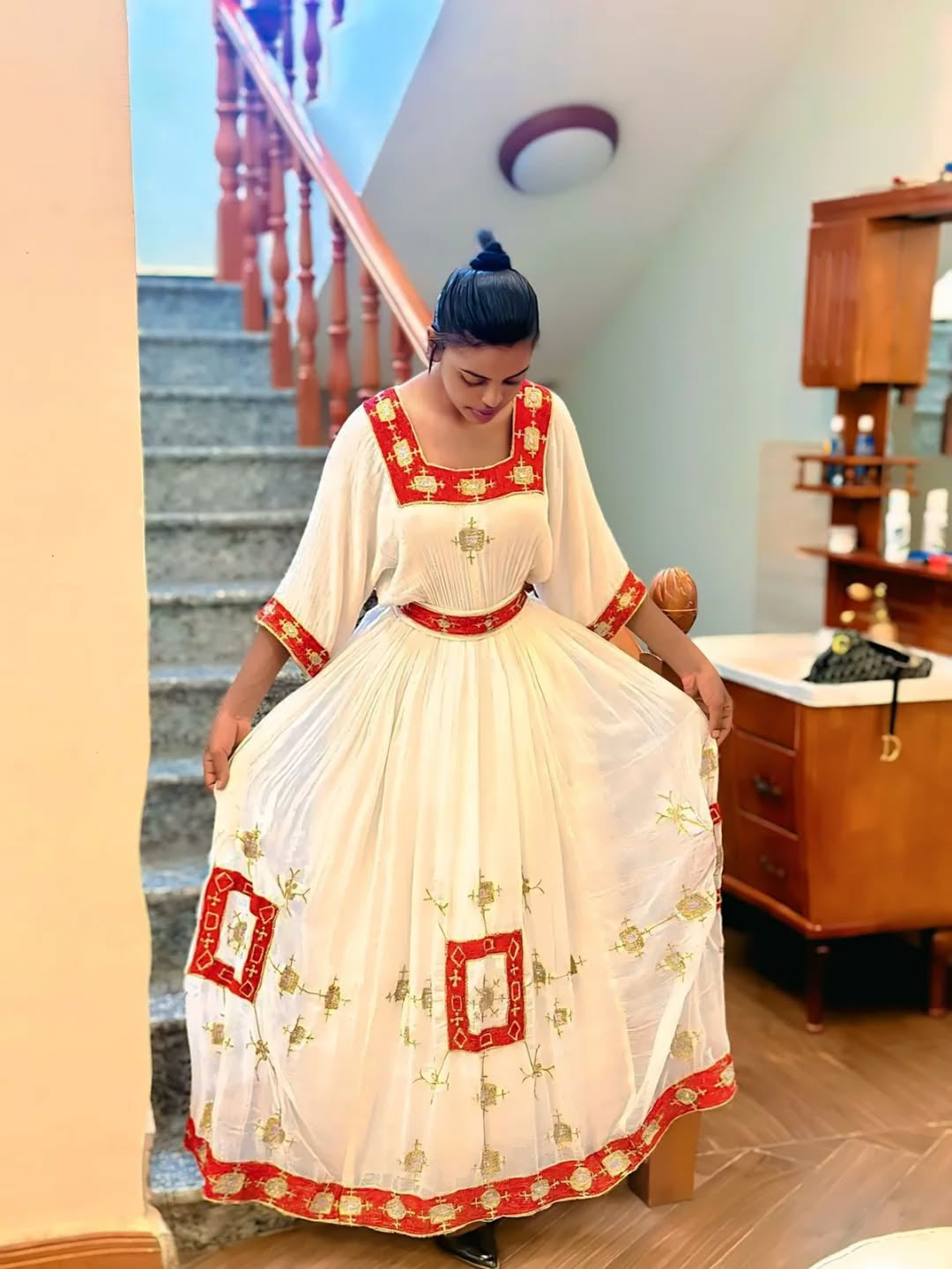 Woman in a Ethiopian Dress with red and white patterns in an indoor setting.