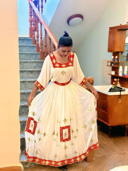 Woman in a Ethiopian Dress with red and white patterns in an indoor setting.