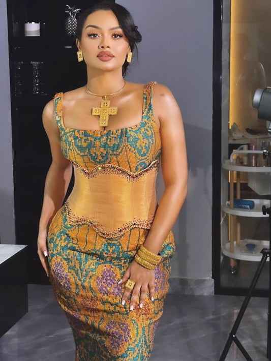 Woman posing in a fitted, sleeveless Ethiopian Dress featuring a gold corset bodice with green and purple patterned embroidery (tibeb).